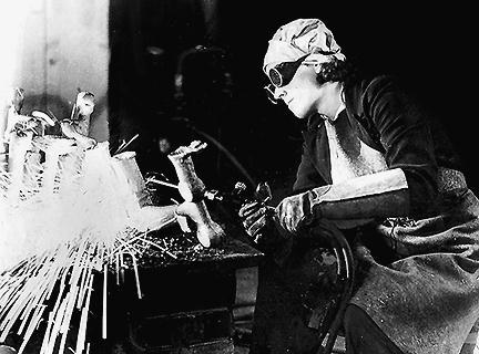 Женщина, квалифицированный токарь, на военном заводе.