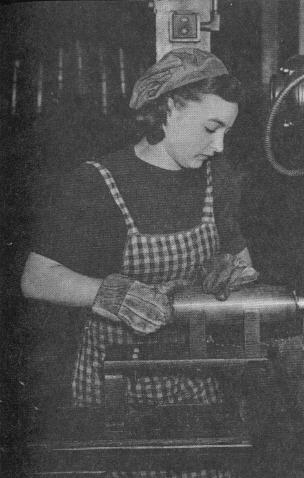 Женщина-токарь обтачивает нос снаряда.